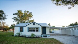 A single-story house with a covered porch, a small front yard, and a gravel driveway. - Coot Bay Cottage at Lake Okeechobee (Clewiston)