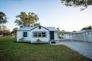 A single-story house with a covered porch, a small front yard, and a gravel driveway. - Coot Bay Cottage at Lake Okeechobee (Clewiston)