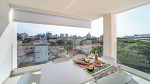 Un balcone moderno con un tavolo da pranzo per due persone, vista sulla città.