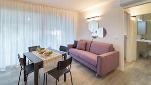 Un soggiorno moderno con un tavolo da pranzo, sedie, un divano rosa e un lampadario a parete.