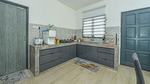 A compact kitchen with dark cabinets, a marble countertop, and a window with blinds. - OYO HOME 90682 Liliz Mambang Farmstay (Pekan)