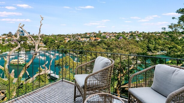 Ein Balkon mit Korbstühlen mit Blick auf einen Hafen und die Stadtlandschaft.
