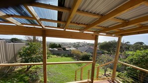 Une terrasse en bois offrant une vue sur un quartier résidentiel, avec des maisons et une cour clôturée.