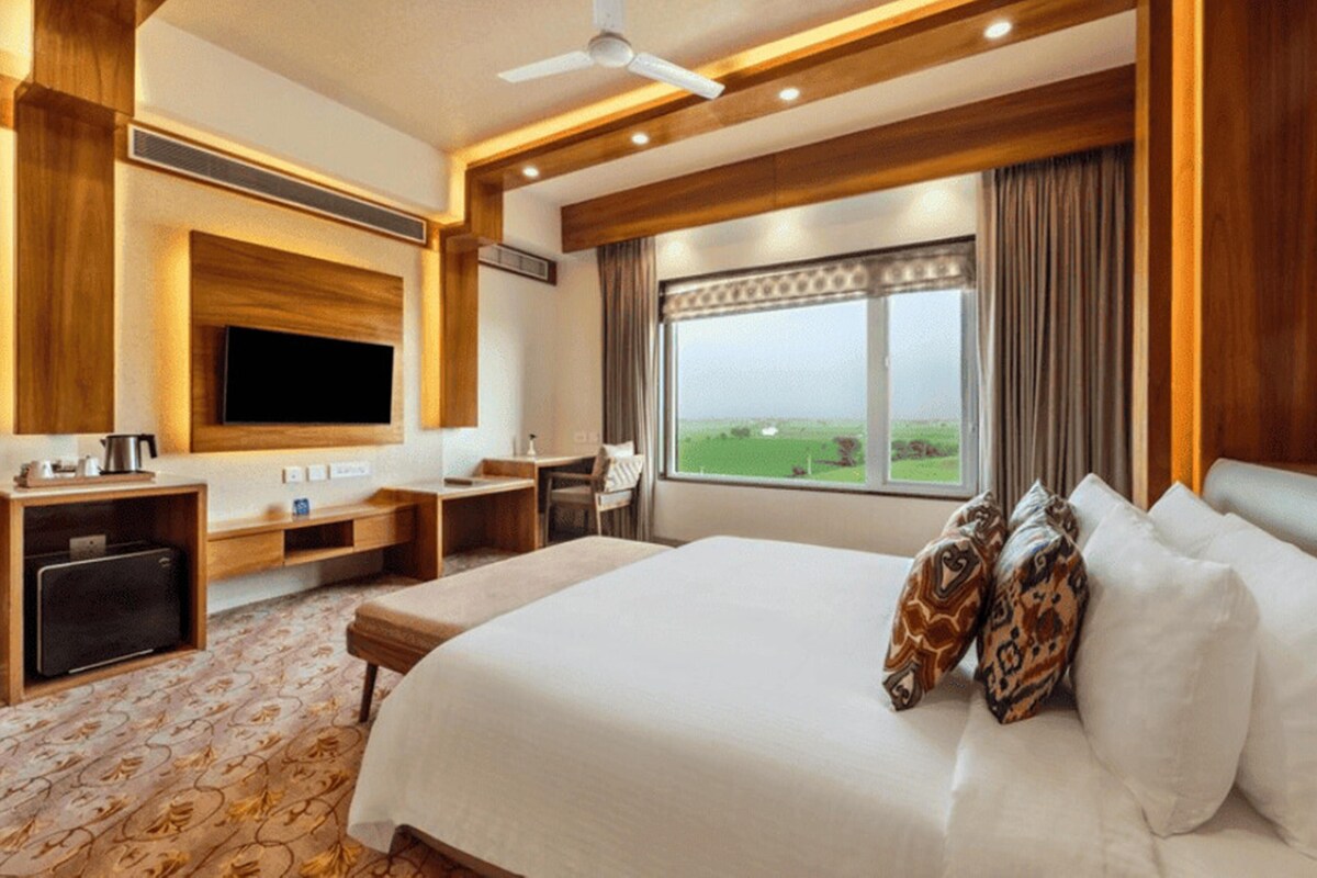 A hotel room with a bed, a desk, a television, and a window with a view.