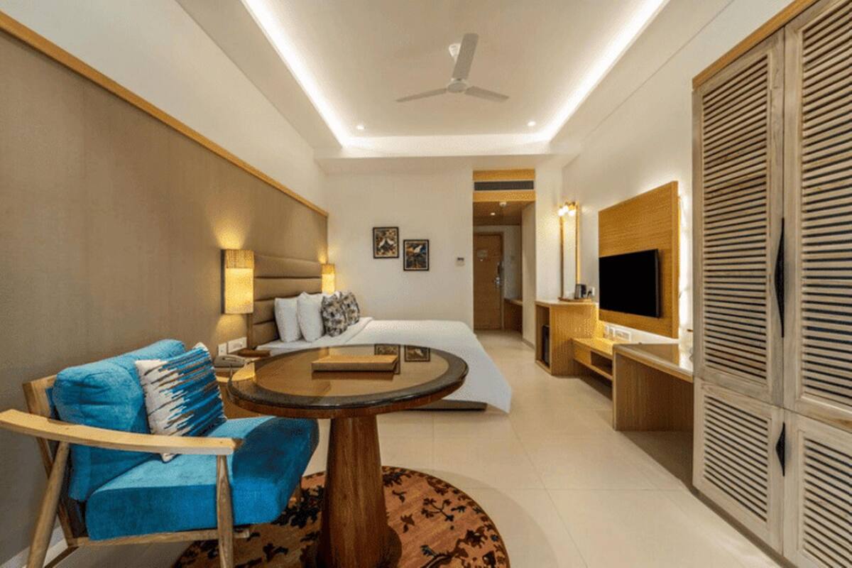 A hotel room with a bed, a desk, a chair, a TV, and a ceiling fan.