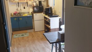 Une cuisine compacte équipée d’un réfrigérateur, d’un four à micro-ondes et d’une machine à café. Elle comprend une petite table et une fenêtre avec vue.