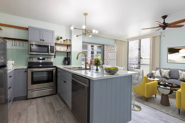 A modern kitchen with a central island, built-in appliances, and a dining area with yellow chairs.