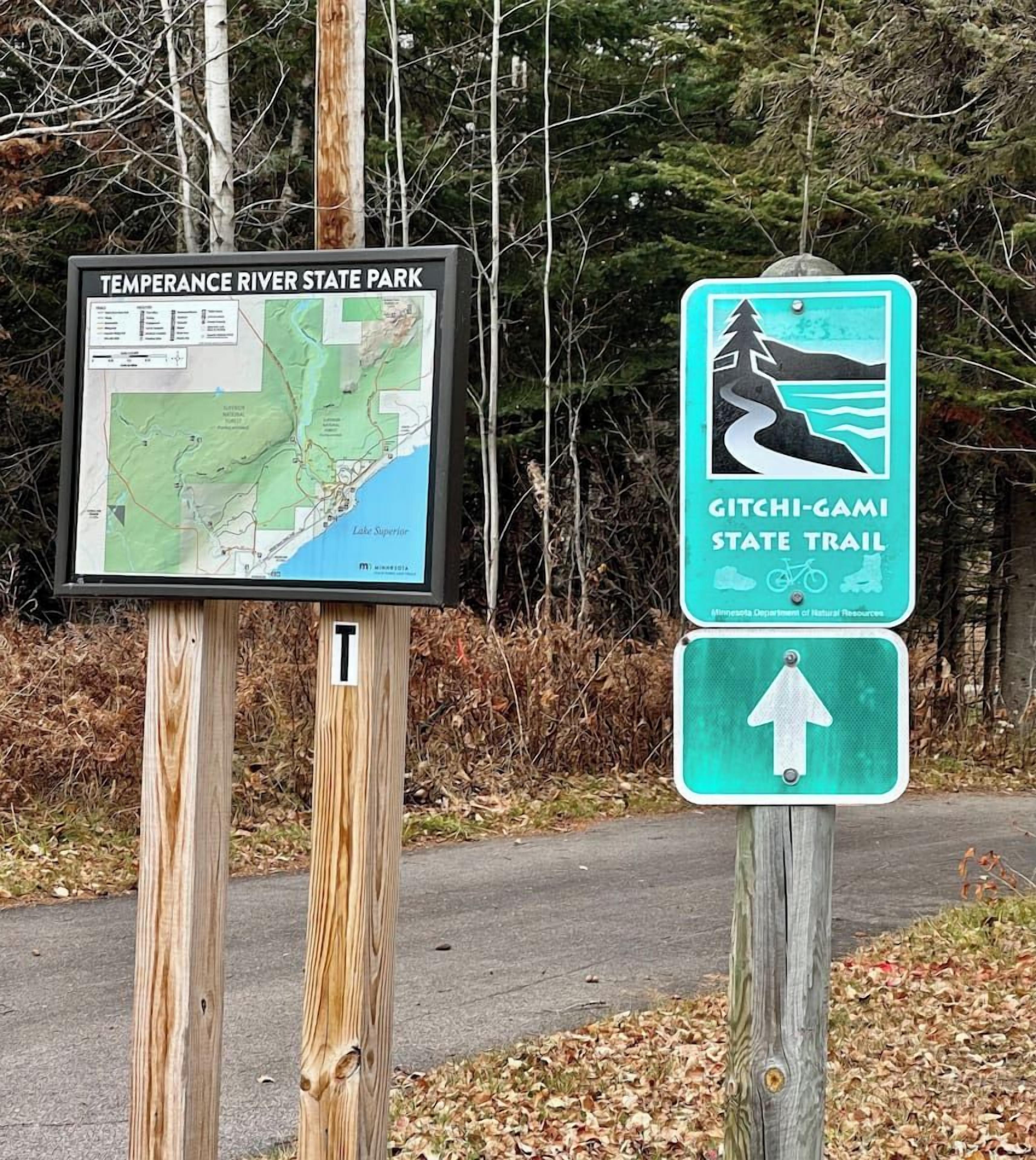 A sign for Temperance River State Park with a map and a trail sign for Gitchi-Gami State Trail.