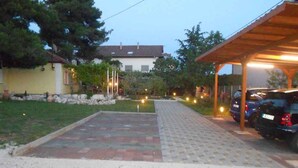A covered parking area with a paved walkway leading to a building. - Holiday home 50 meters from the meter with large garden (Sukošan)