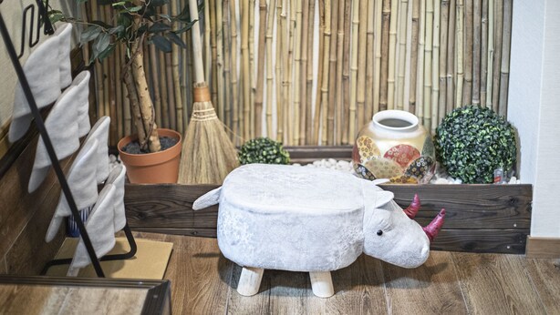 Een kamer met een houten vloer, een wand van bamboe en een klein wit dierenbeeldje.