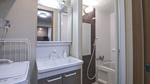 Een moderne badkamer met een witte wastafel, spiegel en douche.