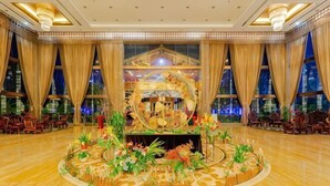 A hotel lobby with a central floral arrangement, large windows, and a chandelier. - Guowei Hotel (Menghai)