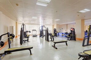 A gym with various exercise equipment, including treadmills, weight machines, and benches. - Guowei Hotel (Menghai)