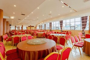 A large banquet hall with multiple round tables and red chairs, arranged in rows. - Guowei Hotel (Menghai)
