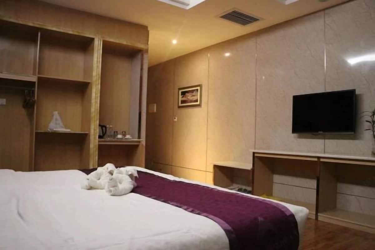 Habitación de hotel con cama, televisor y estanterías empotradas.