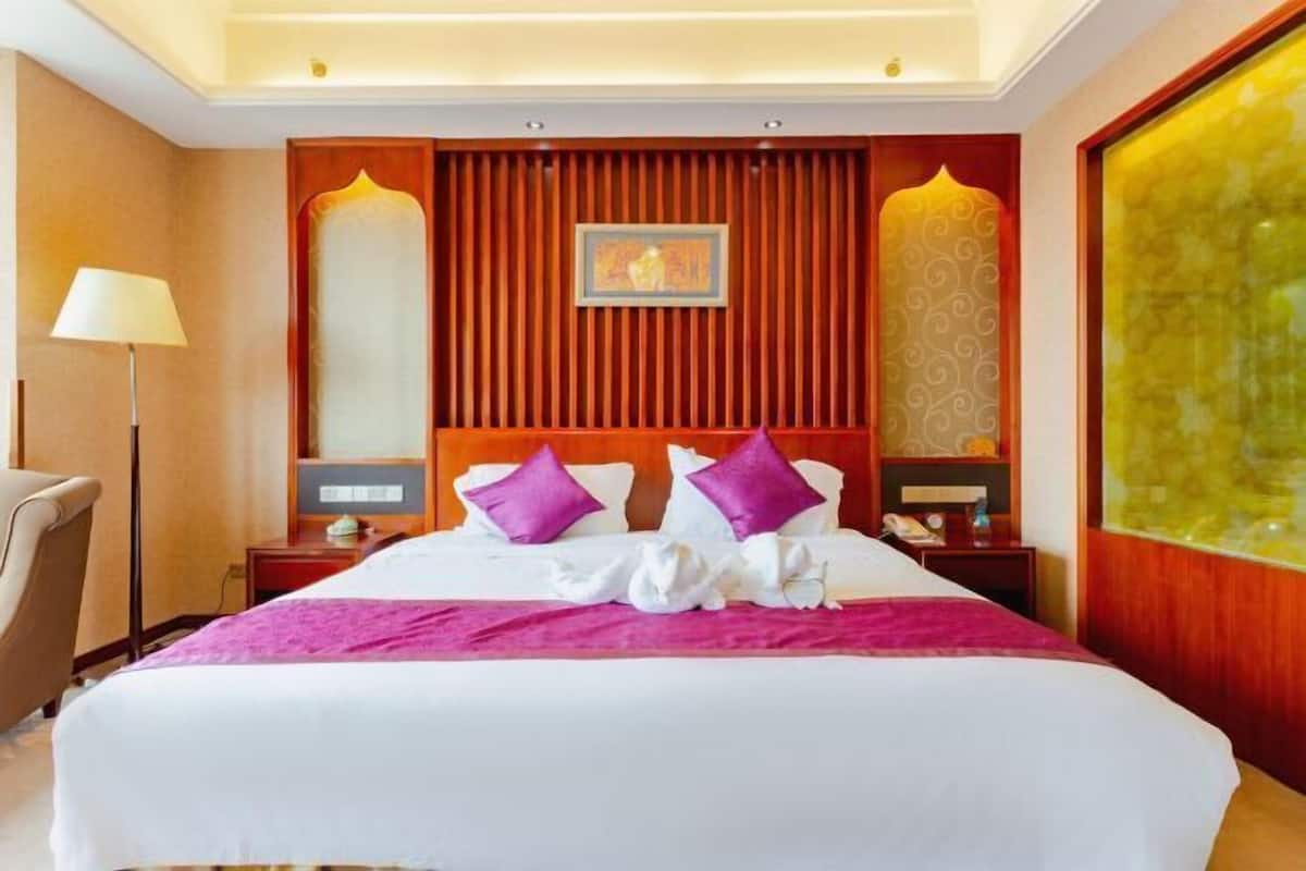 Habitación de hotel con una cama grande, una mesita de noche, una lámpara y una pared decorada con un panel.