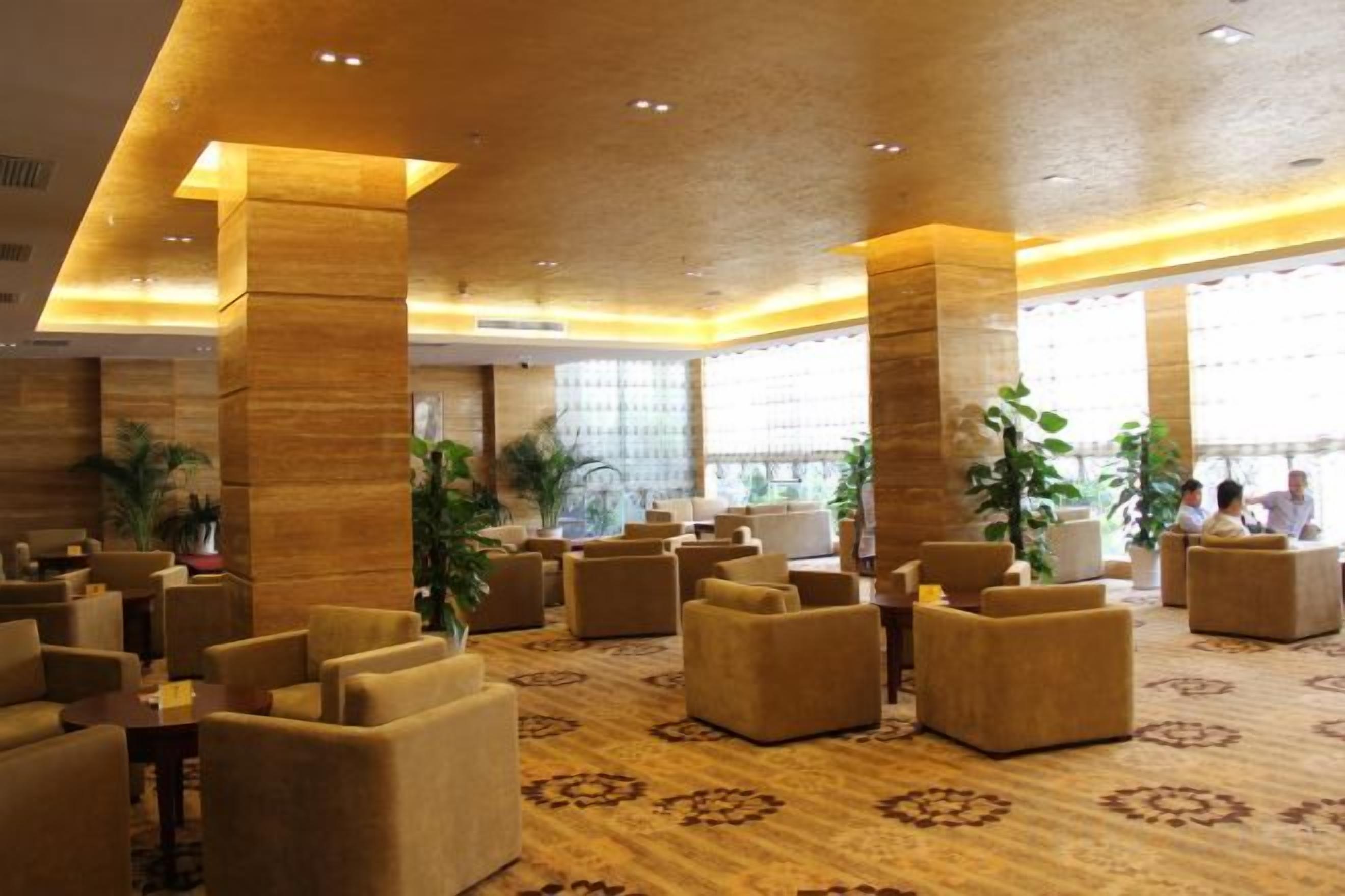 A spacious lobby with multiple seating areas, large pillars, and a patterned carpet.