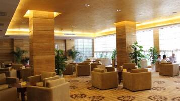 A spacious lobby with multiple seating areas, large pillars, and a patterned carpet.