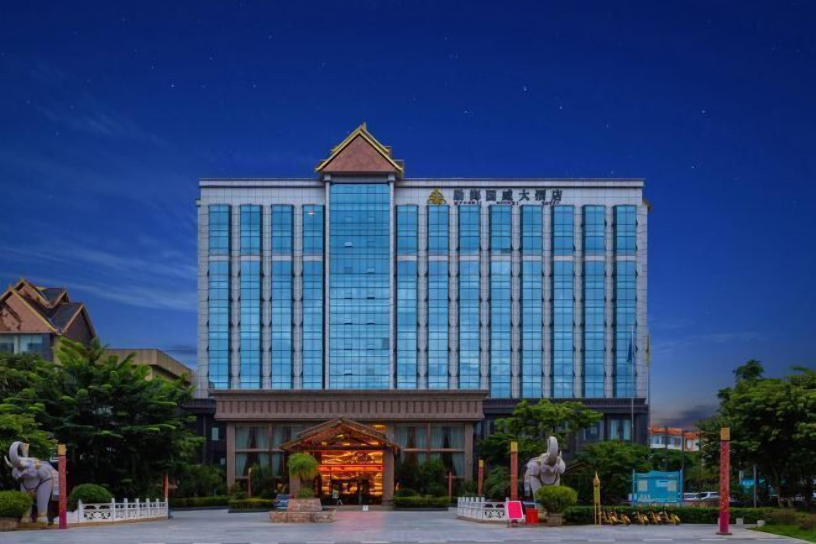 A large hotel building with a prominent entrance and a well-maintained garden area.