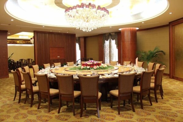 A conference room with a round table, chairs, and a chandelier. - Guowei Hotel (Menghai)