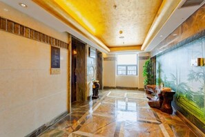 Un vestíbulo de hotel con piso de mármol, una recepción y un mural en la pared.