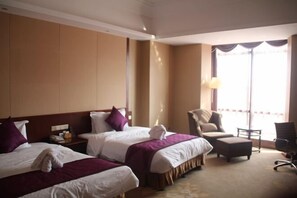 A hotel room with two beds, a chair, an ottoman, and a large window with curtains. - Guowei Hotel (Menghai)