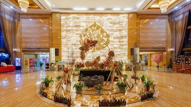 A spacious lobby with a central decorative area, a reception desk, and a modern interior design. - Guowei Hotel (Menghai)