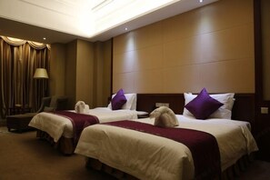 A hotel room with two beds, a chair, a lamp, and a curtain. - Guowei Hotel (Menghai)