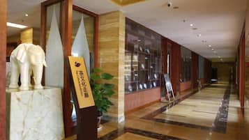 A hotel lobby with a marble floor, a reception desk, and a statue of an elephant.
