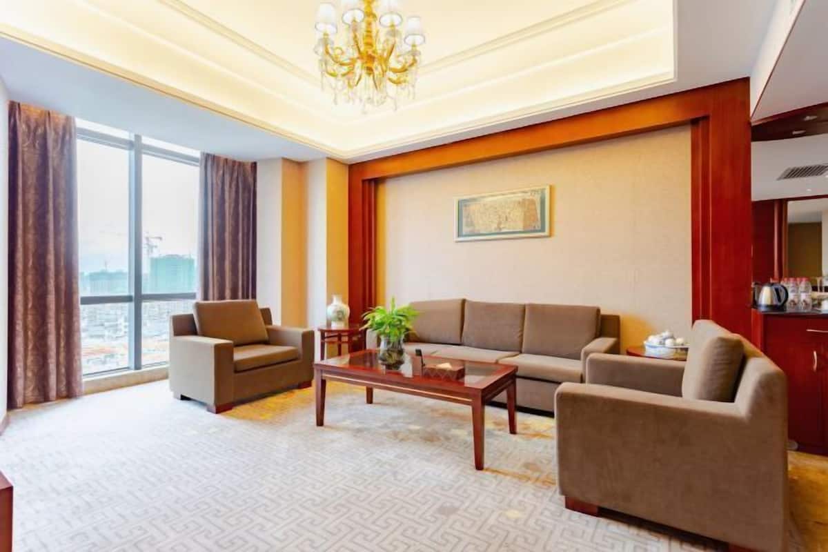 Una sala de estar moderna con un sofá, sillones, una mesa de centro y vistas a la ciudad a través de amplios ventanales.