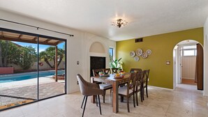 A dining area with a table set for four, a large window with a view of a swimming pool, and a wall with decorative plates. - Southwestern Paradise, Simply Classic (Oro Valley)