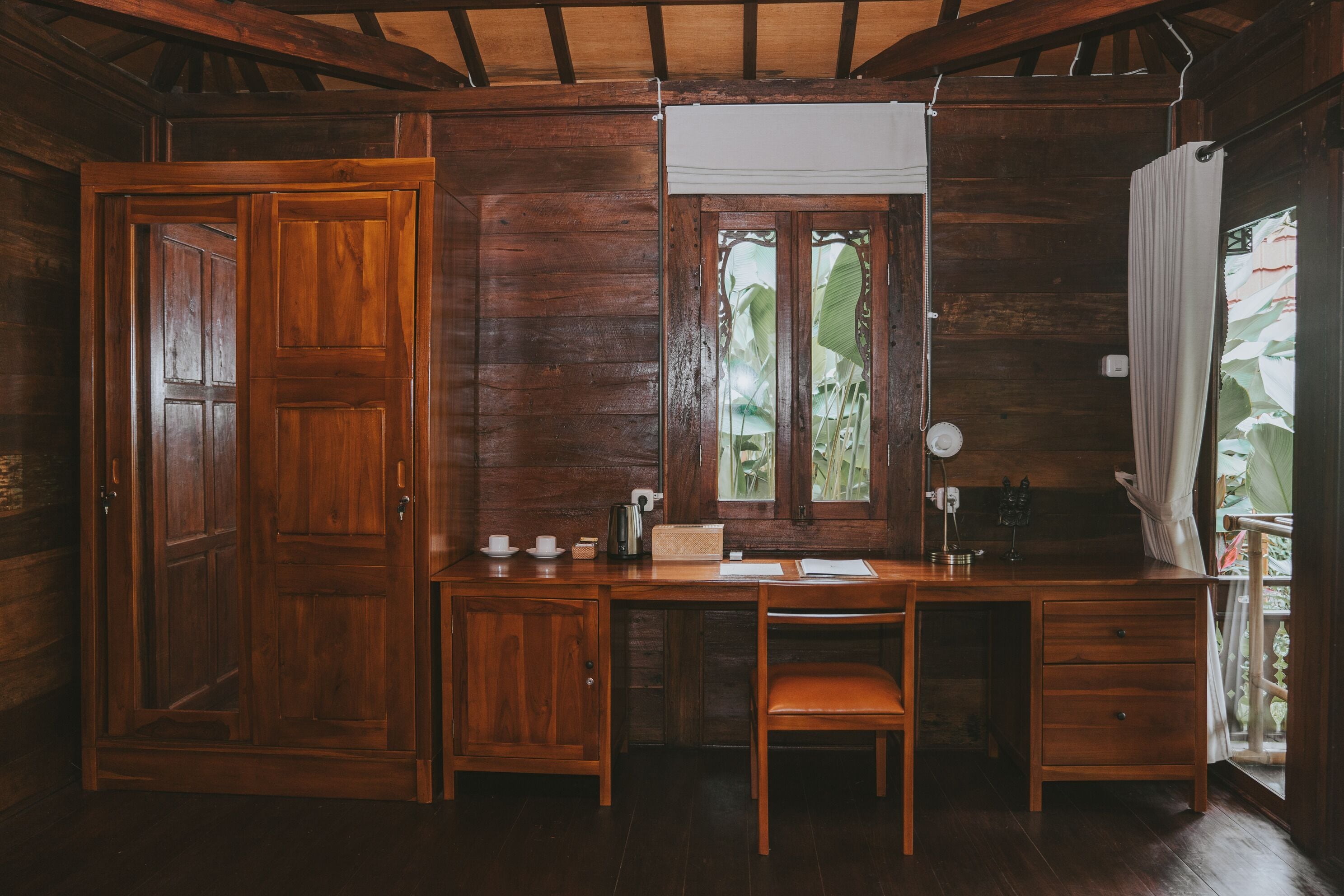 Une pièce en bois avec un bureau, une chaise et une fenêtre donnant sur un paysage verdoyant.