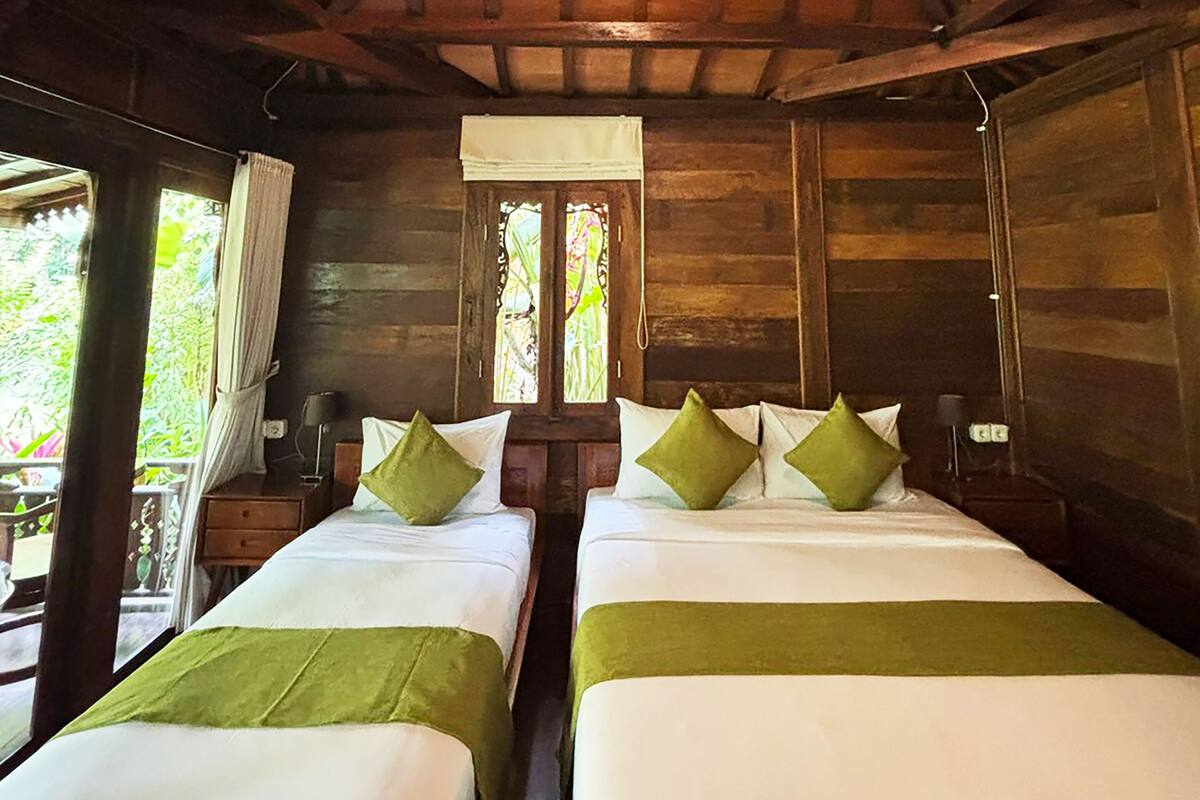 A wooden cabin with two beds, a window, and a ceiling light.