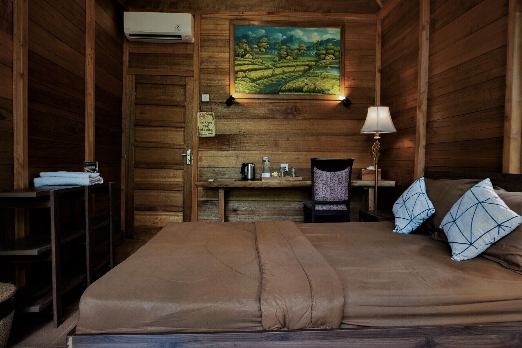 Une pièce en bois avec un lit, un bureau, une chaise et un tableau accroché au mur.