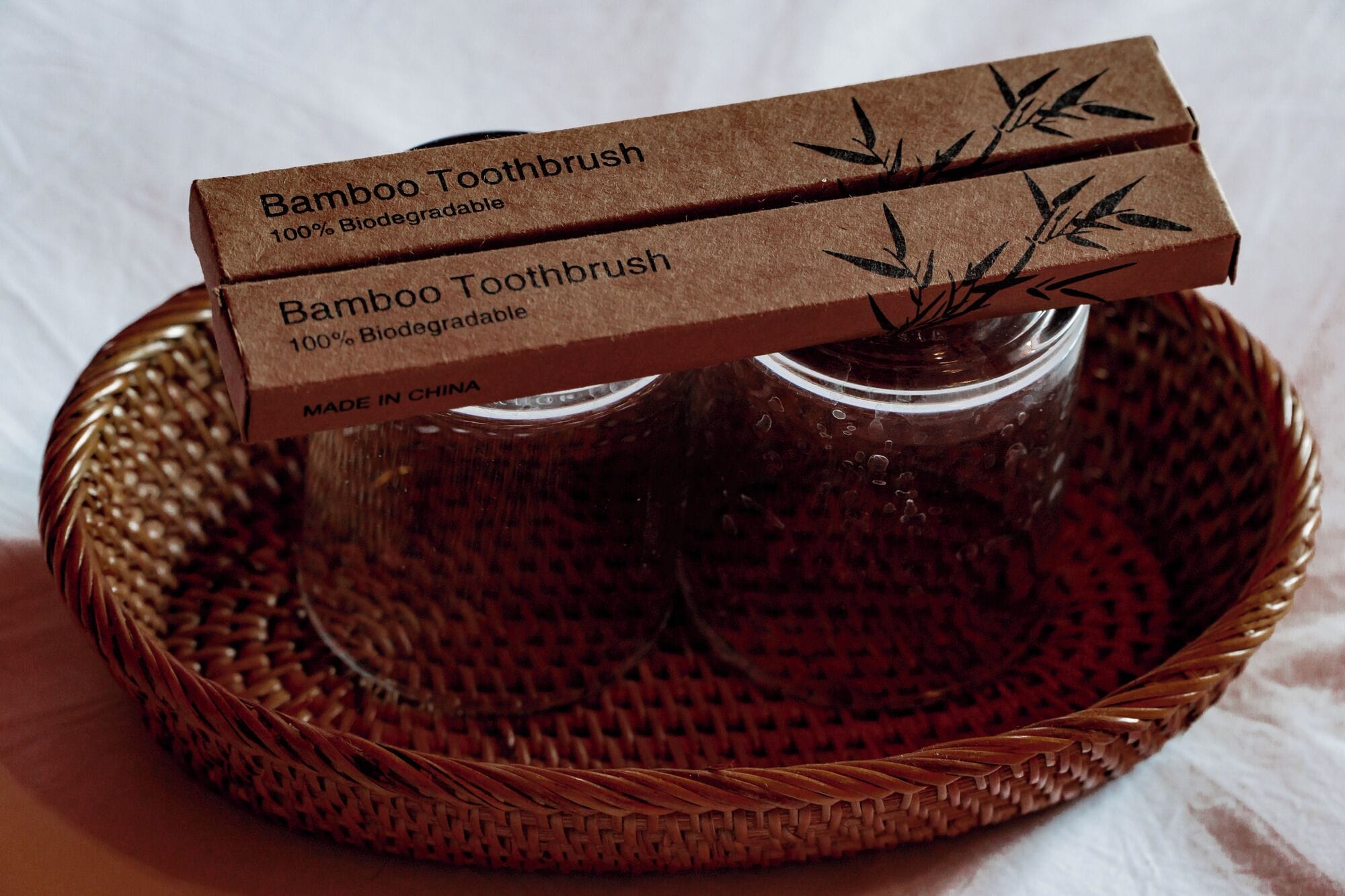 A bamboo toothbrush in a brown box labeled 'Bamboo Toothbrush 100% Biodegradable' and 'Made in China'.