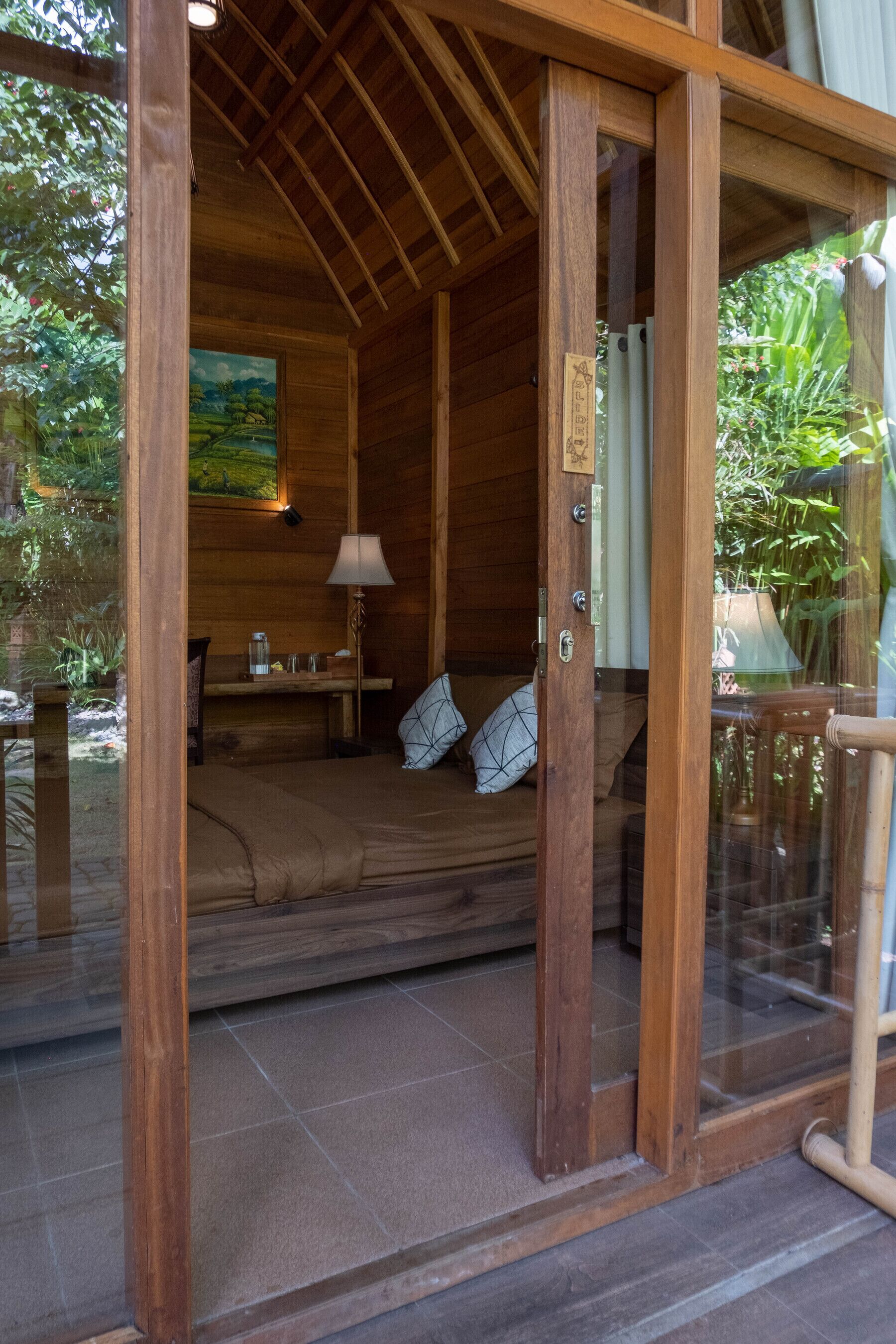 A wooden cabin with a bed, a desk, and a painting on the wall.