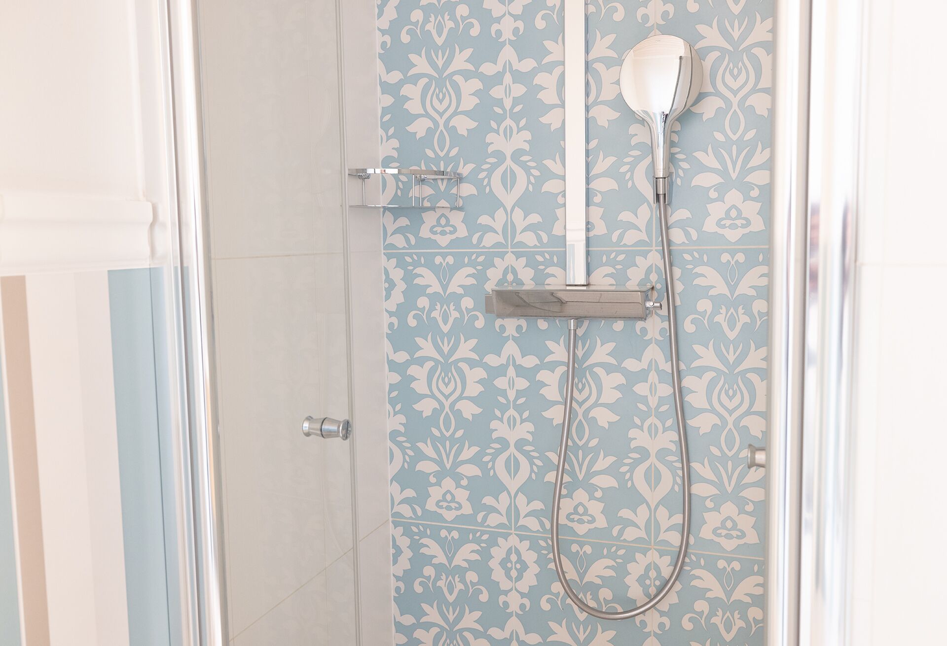 A shower with a handheld showerhead and a wall-mounted faucet.