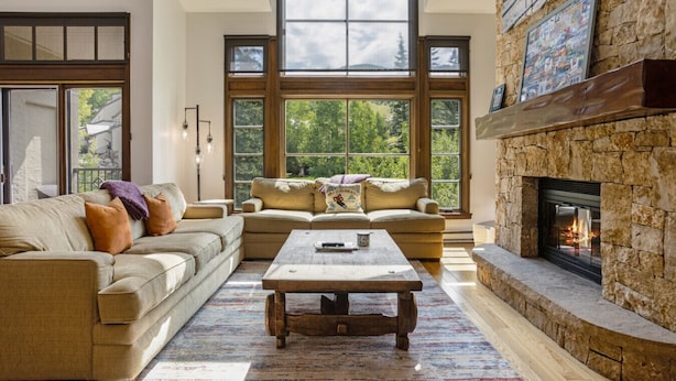 A spacious living room with a large sectional sofa, a wooden coffee table, and a stone fireplace. - Steps From Slopes - Luxury Beaver Creek Townhome (Beaver Creek)