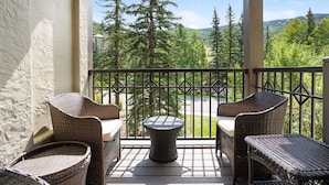 A balcony with wicker furniture, a round table, and a view of a forested area. - Steps From Slopes - Luxury Beaver Creek Townhome (Beaver Creek)