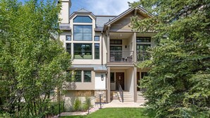 A two-story house with a balcony, a stone facade, and a well-maintained lawn. - Steps From Slopes - Luxury Beaver Creek Townhome (Beaver Creek)