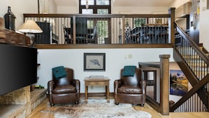 A spacious living area with a high ceiling, a wooden staircase, leather armchairs, a flat-screen TV, and a large rug. - Steps From Slopes - Luxury Beaver Creek Townhome (Beaver Creek)