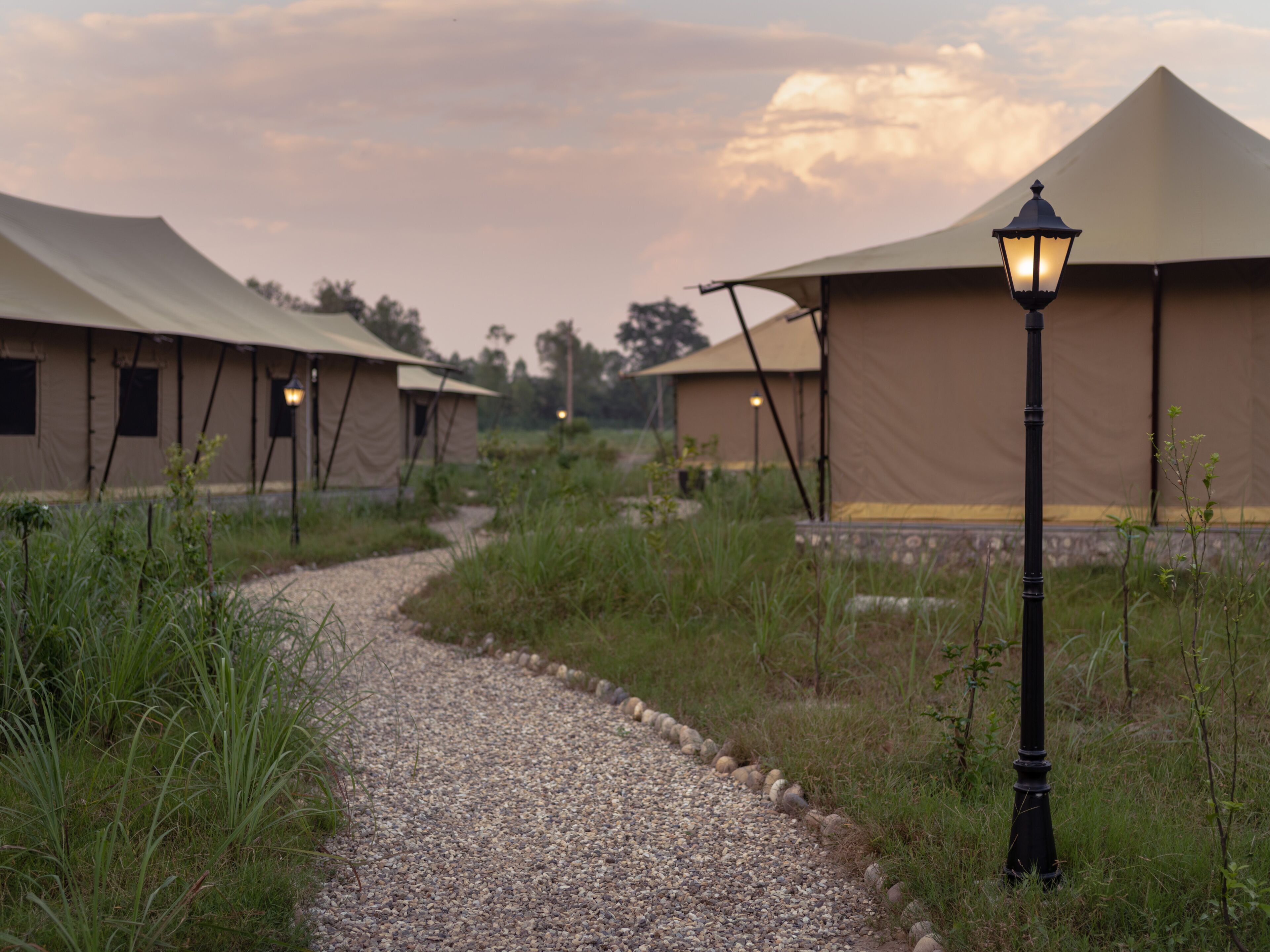 A pathway leading to a series of tents with a lamp post in the foreground.