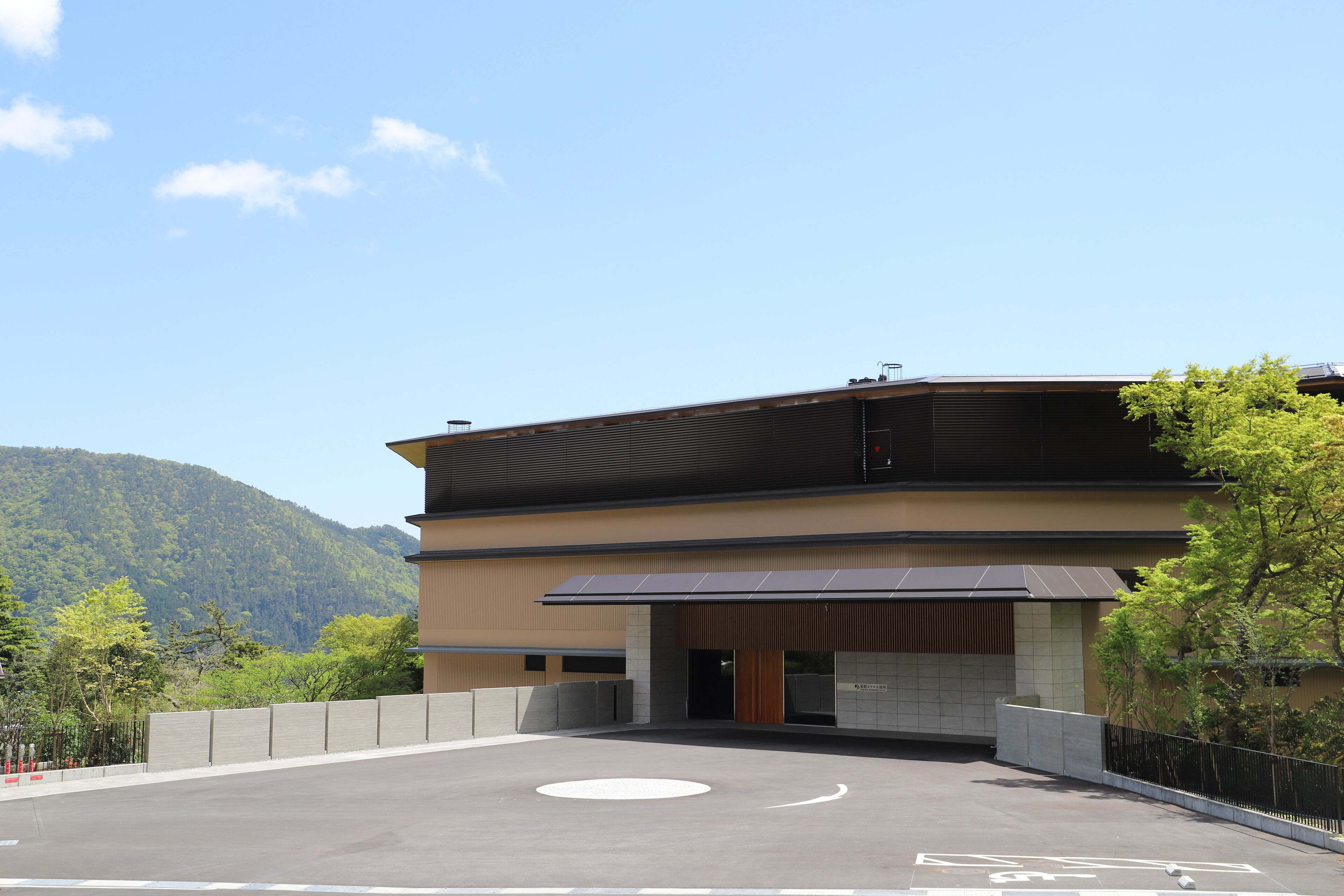 Un edificio moderno con tetto piatto, ampie finestre e un'area di parcheggio con un cerchio bianco.