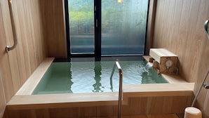Una sauna con suelo de madera, puerta de cristal, banco de madera y estufa de madera.