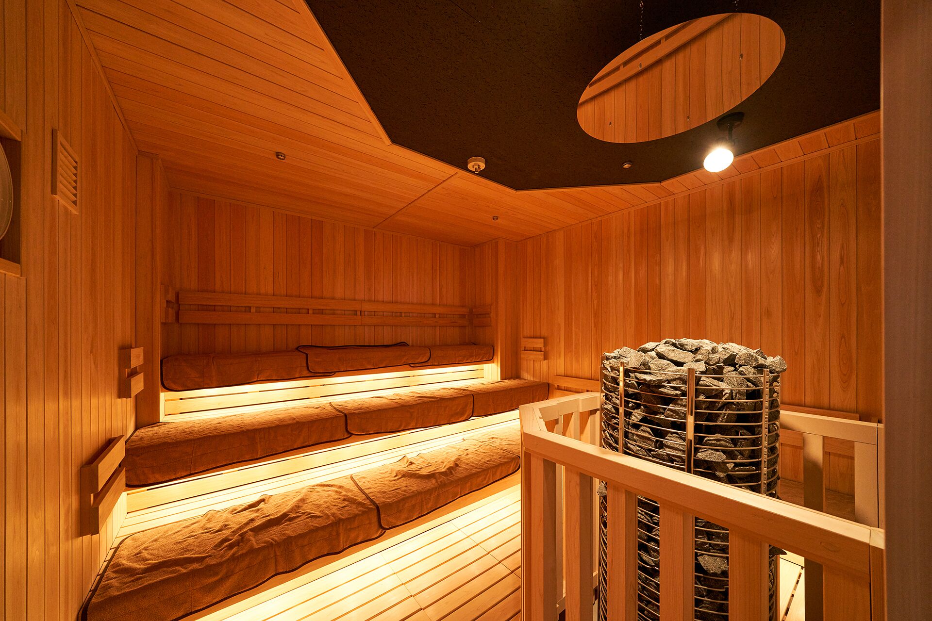 A wooden sauna with benches and a stone heater.