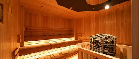 A wooden sauna with benches and a stone heater.