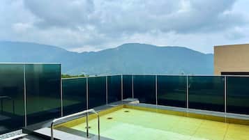 A rooftop pool with glass railings and a view of mountains.