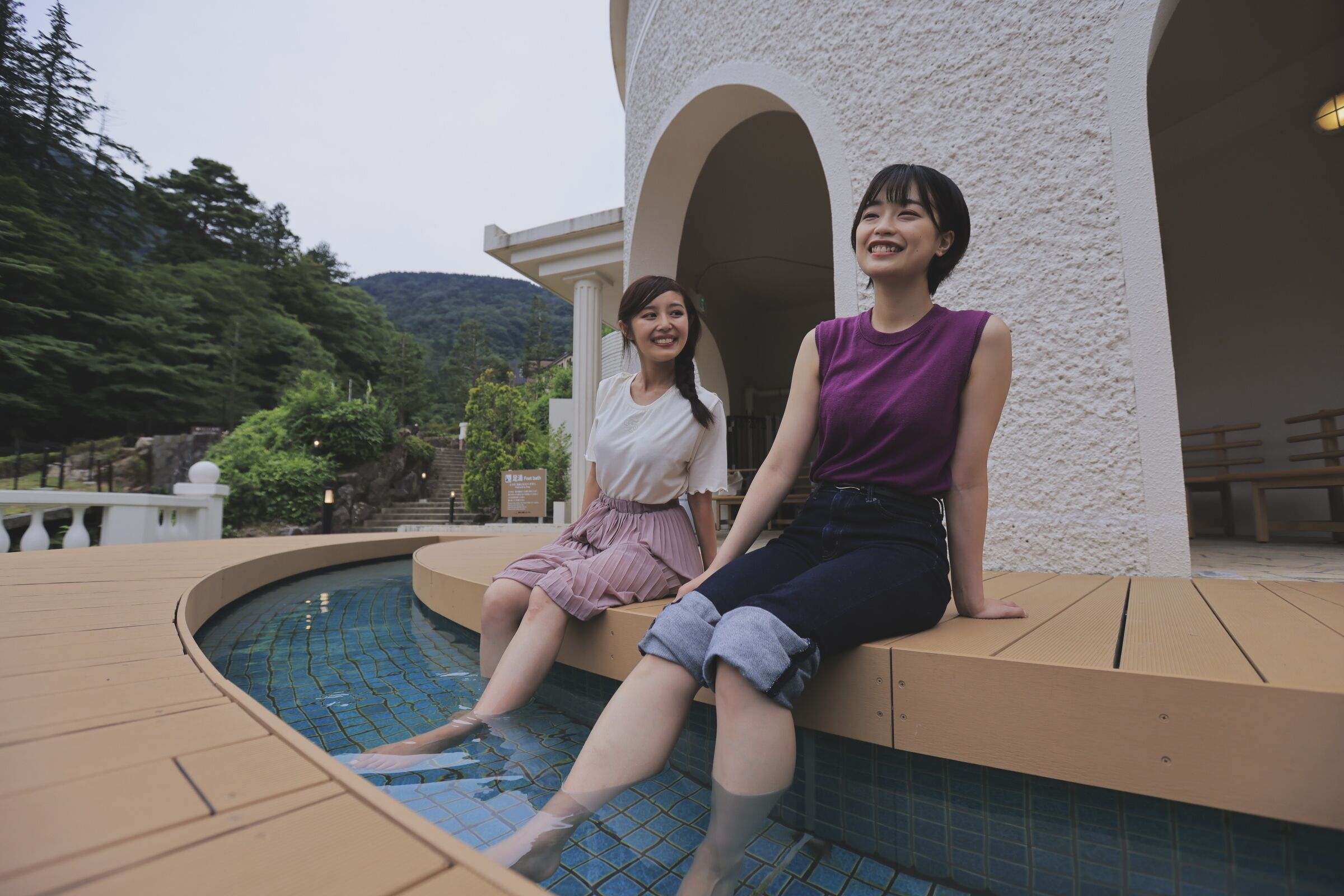 Two people sitting by a pool with a white building in the background.