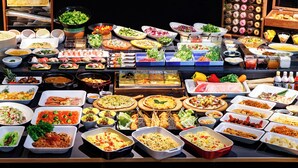 Un bufé con diversos platos, entre ellos sushi, ensaladas y pasta.