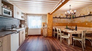 Eine gemütliche Küche mit Holzböden, einem Essbereich mit Tisch und Stühlen sowie einem Fenster mit Vorhängen.